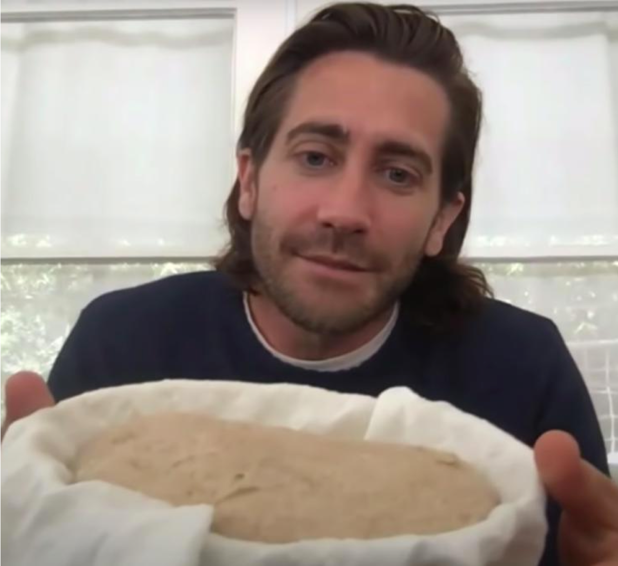 Jake Gyllenhaal holding a tub of sourdough starter